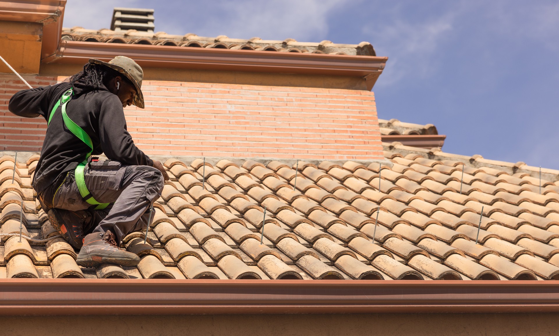 Technician installing photovoltaic solar panel mounting structure on roof of house