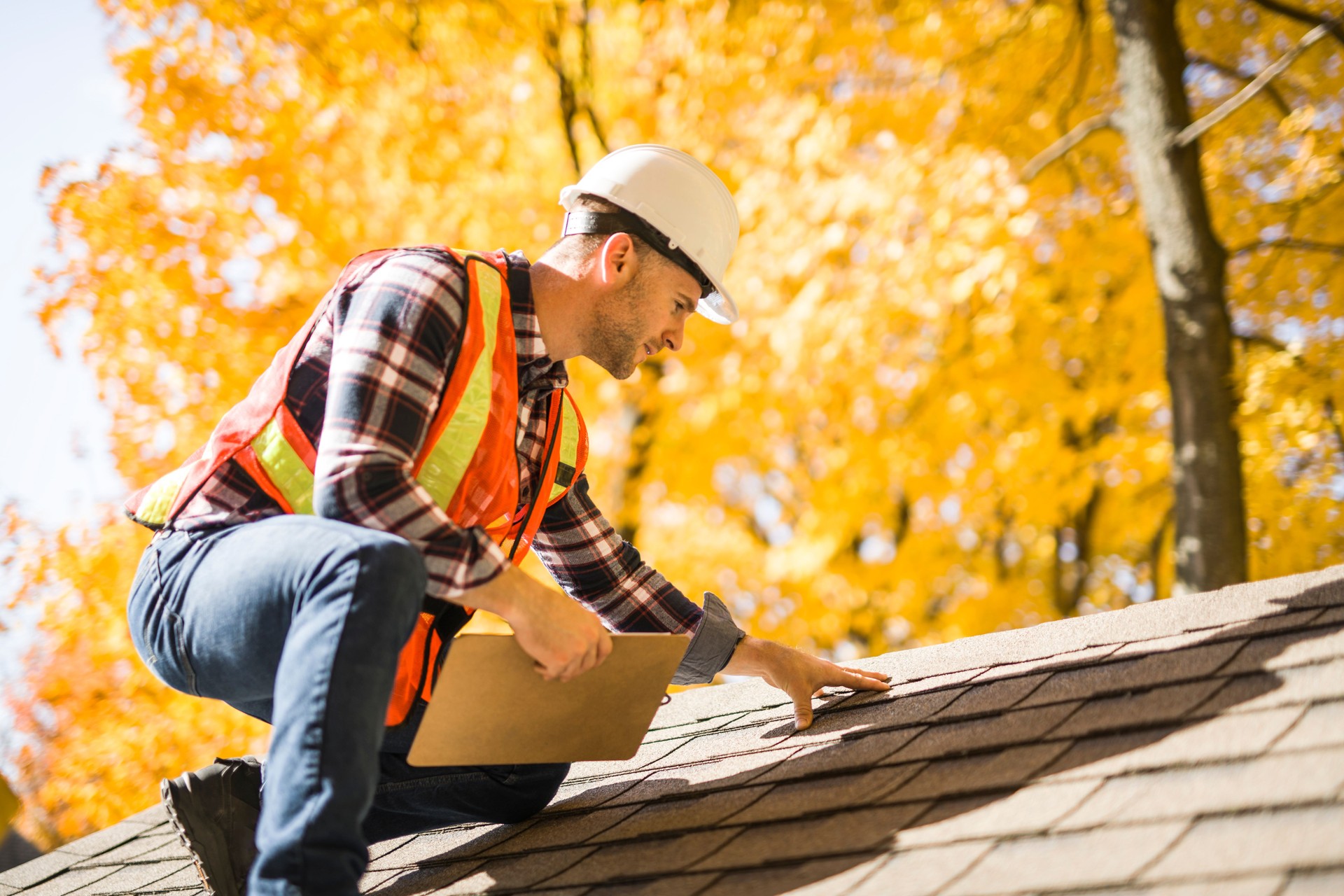 man with hard hat standing on steps inspecting house roof